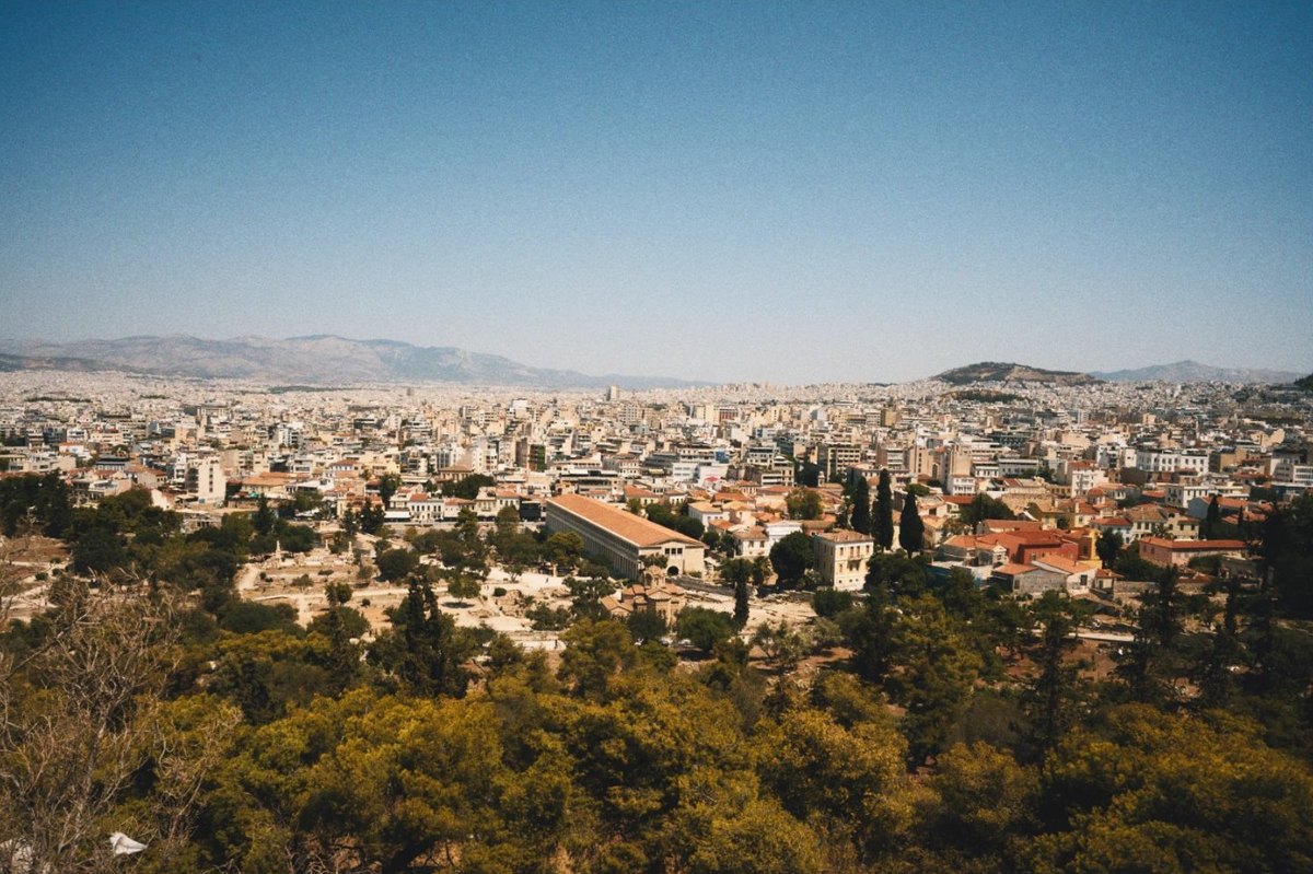 Sample photo: Athens from above, with terracotta roofs under a blue sky and pine trees in front.